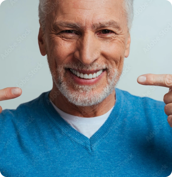 A smiling older man pointing at his restored smile